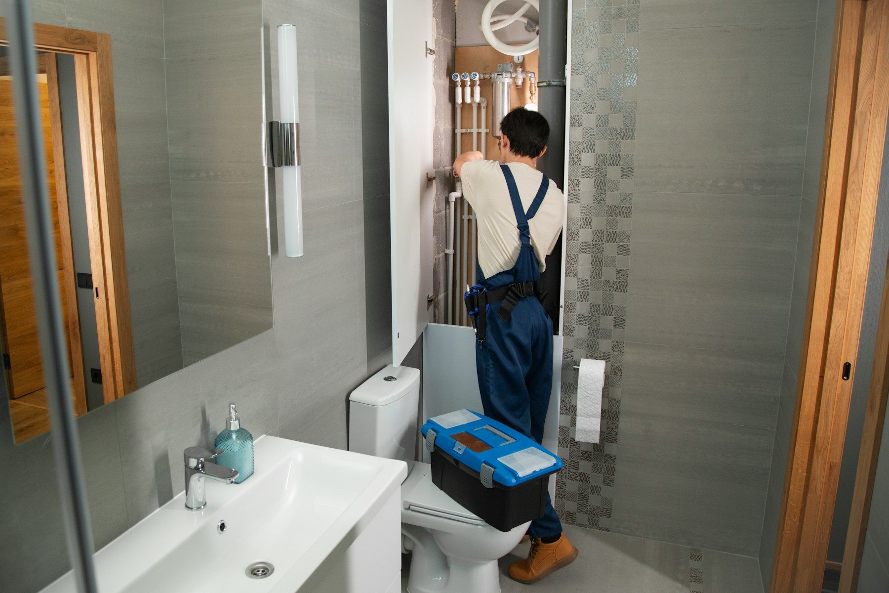 A plumber repairing pipework in a residential bathroom.