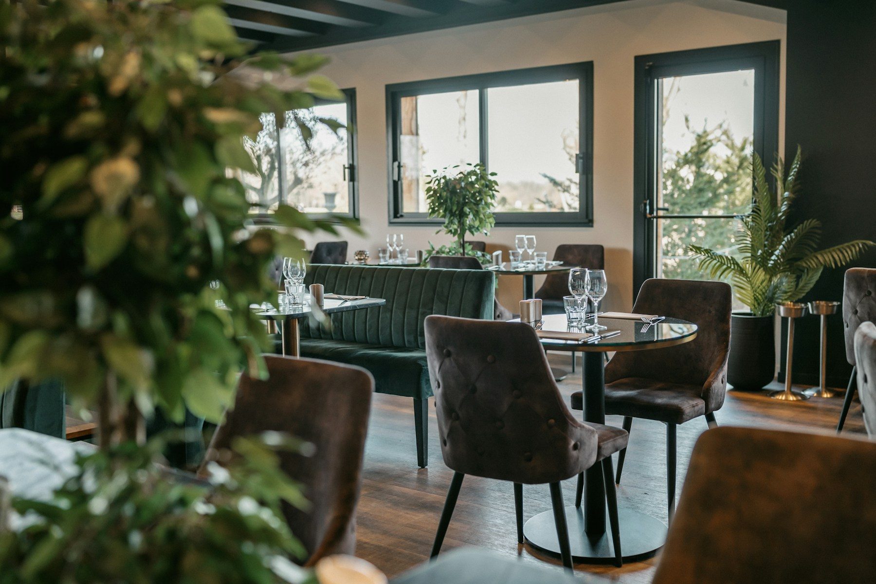 A warmly lit neighborhood restaurant dining room with tables set for guests.